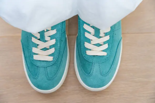 stock image A top view of womens feet in turquoise sneakers, showcasing a trendy and casual fashion style. The vibrant color and casual setting convey a youthful and relaxed lifestyle, perfect for daily wear.