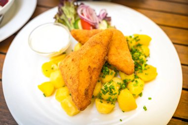 Patatesli kızarmış gouda peyniri, küçük bir kase sos ve taze salata garnitürle servis edilen lezzetli bir Çek yemeği..