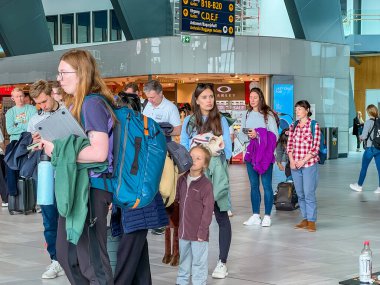 Bergen, Norveç - 12 Temmuz 2024: Yolcular havalimanı terminalinde bekliyor. Gezginler ve bavullarıyla dolu yoğun bir bekleme alanı, seyahat atmosferini ön plana çıkarıyor..