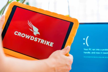Prag, Çek Cumhuriyeti - 25 Temmuz 2024: Bir kadın, Windows mavi ölüm ekranının yanında CrowdStrike siber güvenlik yazılımına sahip. Dijital koruma ve bilgisayar sorunları.