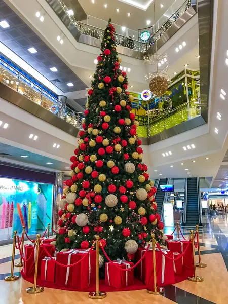 Antalya, Türkiye - 11 Aralık 2016: Kırmızı ve altın süslemelerle süslenmiş, Antalya alışveriş merkezinde dimdik duran, festival süslemeleri ve hediye kutularıyla çevrili büyük bir Noel ağacı