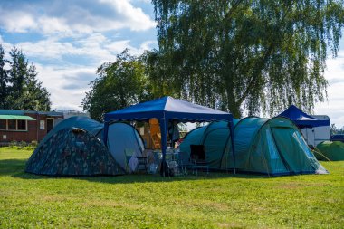 Nova Zivohost, Çek Cumhuriyeti - 5 Ağustos 2024: Çek Cumhuriyeti 'nin Slapy kentindeki yeşil bir çayırda huzurlu bir kamp sahnesi. Çadırlar Vltava nehrinin yanında çimenli sahilde kurulmuş.