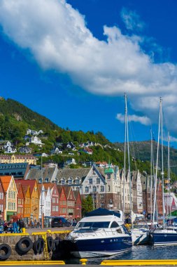 Bergen, Norveç - 9 Temmuz 2024: Bergen, Norveç 'te yaz güneşli bir günde Bryggen - geleneksel kırmızı ahşap evler sergilenir. Yat limanının renkli tarihi simgesi.