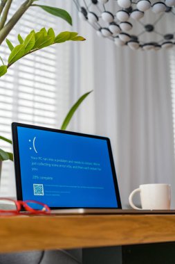 Prag, Çek Cumhuriyeti - 13 Eylül 2024: İç ofis masasında kullanılmakta olan bir dizüstü bilgisayar, bir sistem çökmesinin sinyalini veriyor. Çalışma alanı bir kupa ve lambayla düzenlenir..