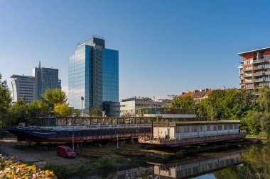 Prag, Çek Cumhuriyeti - 20 Eylül 2024: Selden sonra Holesovice bölgesinde sakin bir manzara, nehir boyunca yanaşan tekneler ve sulara yansıyan modern apartmanlar.