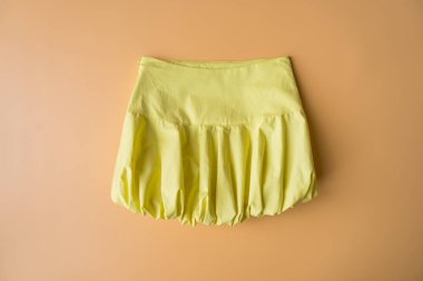 Yumuşak şeftali rengi arka planda balon silueti sergilenen tereyağı sarısı bir mini etek. Bu canlı ve neşeli parça 2024 yazının bir parçası. Hızlı moda trendi, cesur şekilleri vurguluyor.. 