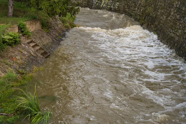 stock image Prague, Czech Republic - September 16, 2024: A picturesque scene featuring the small river Rokytka in Palmovka district. The rushing waters reflect the threat of impending floods on a cloudy day.