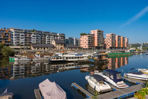 Prague, Czech Republic - September 20, 2024: A calm scene in Holesovice district after a flood threat, with boats docked along the river and modern apartment buildings reflecting in the water.