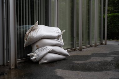 White sandbags are placed by the entrance of a contemporary building in Prague to protect against potential flooding. Storm Boris. clipart