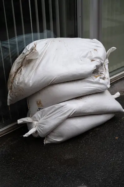 stock image White sandbags are placed by the entrance of a contemporary building in Prague to protect against potential flooding. Storm Boris.