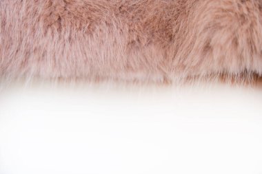 Sıcak, şeftali rengi olan sahte bir kürk mantonun yakın çekimi. Kumaşın kabarık dokusu konfor ve sıcaklık hissi veriyor. Soğuk aylar boyunca rahat moda için ideal..