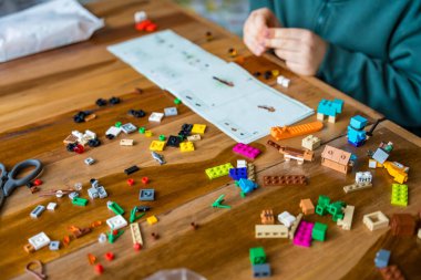 Çek Cumhuriyeti, Krecivice - 31 Aralık 2023: Koyu turkuaz kazaklı yüzsüz bir ilkokul öğrencisi talimatlara göre LEGO Minecraft 'ı dikkatlice monte ediyor.