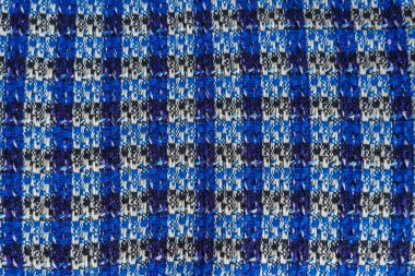 Karmaşık desenli ve yumuşak kıvrımlı damalı mavi ve siyah kumaşın yakın çekim görüntüsü. Tekstil geri dönüşümü, sürdürülebilir moda ve moda endüstrisinde aşırı üretim kavramları.