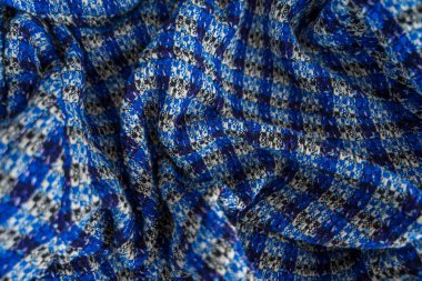 Ayrıntılı dokusu ve yumuşak kıvrımları olan katlanmış mavi ve siyah kareli kumaş. Canlı renkler sürdürülebilir moda, geri dönüşüm, ekolojik bilinçli tekstil üretimi temalarını vurguluyor