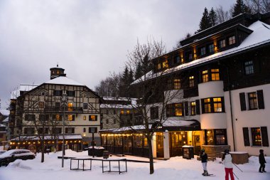 Spindleruv Mlyn, Çek Cumhuriyeti - 3 Ocak 2025: Lüks otellerin kış manzarası Savoy ve Soyka 'nın parlak ışıkları, karla kaplı çatıları, dağlık bir tatil beldesindeki atmosferin keyfini çıkaran kayakçılar