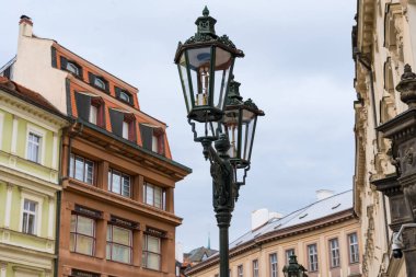 Prag, Çek Cumhuriyeti - 11 Ekim 2024: Nove Mesto 'da Avrupa mimari ayrıntılarına sahip tarihi binalarla çevrili süslü bir siyah demir sokak lambasına yakın çekim. 