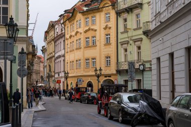 Prague, Czech Republic - October 11, 2024: A lively street in the historic center with pastel-colored buildings, vintage cars, and pedestrians. Celetna street clipart