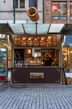 Prag, Çek Cumhuriyeti - 11 Ekim 2024: Bir satıcı Nove Mesto 'da bir sokak yemeği standında popüler bir Çek hamur işi olan Trdelnik' i hazırlıyor. Son büfe Na Prikope klasik tabelayla süslenmiş..
