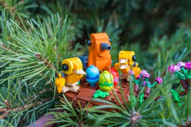 Osnice, Çek Cumhuriyeti - 28 Temmuz 2024: Ahşap bir üste, ladin dalında papatyalarla çevrili renkli oyuncak kuşların olduğu bir Lego piknik sahnesinin yakın çekimi