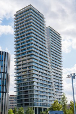 Prag, Çek Cumhuriyeti - 28 Temmuz 2024: Camdan cepheli ve yeşil çevresi olan modern V Kulesi gökdelenleri. Pankrac 'ta mavi gökyüzü altında çağdaş mimarisi olan uzun konutlar..