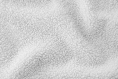 Yumuşak ve rahat beyaz şerpa yün kumaşı geri dönüşümlü polyesterden yapılmış, dalgalı dokusunu ince detaylarıyla yakalıyor. Yakın çekim, yumuşak, yumuşak yüzeyi vurgular. Kış kıyafetleri için idealdir.