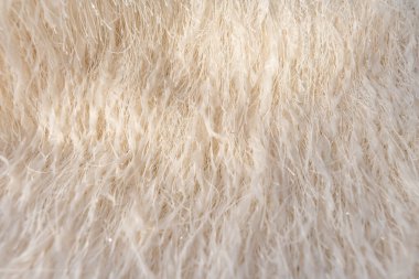 Metalik ipliklerle bej tüylü kumaşın detaylı makro görüntüsü. Hassas dokusu zarif ve lüks bir his yaratıyor. Moda ve iç tasarım için güneş ışığı ile ideal.