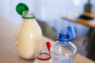 Ahşap bir masanın üzerinde mavi, kırmızı ve yeşil renkli kapaklı üç plastik şişe yakın plan. Gelişmiş geri dönüşüm ve azalan atık için modern ambalaj tasarımı. Seçici odak, doğal ışık