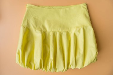 Yumuşak şeftali rengi arka planda balon silueti sergilenen tereyağı sarısı bir mini etek. Bu canlı ve neşeli parça 2024 yazının bir parçası. Hızlı moda trendi, cesur şekilleri vurguluyor.