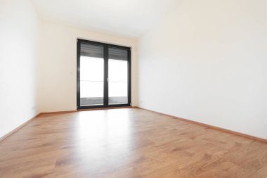 Geniş, parlak bir oda. Çağdaş bir dairede ahşap döşeme ve eğimli bir pencere sistemi var. Büyük pencereler doğal ışık ve şehir manzarası sunar. 