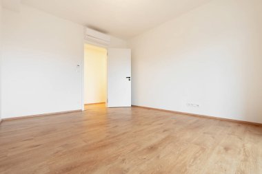 Modern ve davetkar boş bir daire ahşap zemin, beyaz duvarlar ve bir havalandırma ünitesi. Emlak satışı ya da kira için mükemmel. Cömert kopya alanı sunuyor..