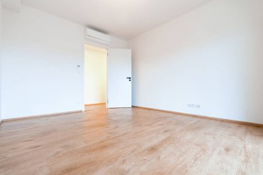 Çağdaş bir dairede, parlak ve havadar boş bir oda, ahşap döşeme ve klimalı beyaz duvarlar. Bir sürü kopya alanı olan emlak kullanımı için ideal.