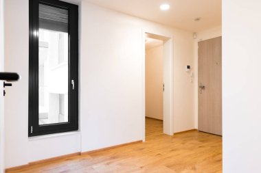 Çek bir apartmanın giriş koridorunun iç manzarası. Ahşap döşeme, eğim ve dönüş sistemi, beyaz duvarlar, doğal ışık. Göz hizasında dengeli bir bakış açısıyla vurulmuş. Kimse yok.