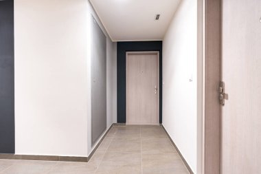 Modern ahşap bir giriş kapısına yakın çekim. Gözetleme deliği ve şık bir apartman koridorunda güvenlik kilidi var. Minimalist tasarım, karanlık ve aydınlık duvarlar. İnsan yok, kopyalama alanı.