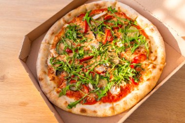 Roka, patlıcan, kırmızı biber, mantar ve peynirli nefis bir pizza. Sıcak ışık, ahşap masa, düz uzanma. Taze vejetaryen fast food. İnsan yok, yemeye hazır.