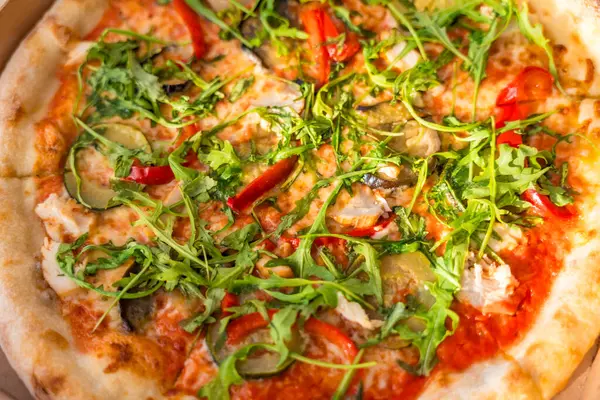 Lezzetli pizzayı roka, patlıcan, kırmızı biber, mantar ve peyniri paket kutusuna koy. Sıcak ışık, ahşap masa, düz uzanma. Taze vejetaryen fast food. Yumuşak ve seçici odak