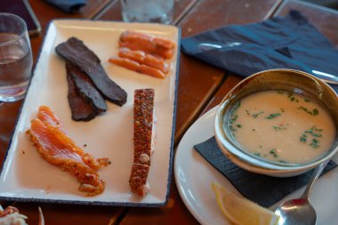 Norveç 'in Bergens ulusal balık pazarında geleneksel Norveç tadım tabağına balina eti, marine edilmiş somon, baharatlı balık ve kremalı balık çorbası. Tahta masada limonla servis edilir.