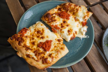 Norveç, Bergen 'de öğle yemeği sırasında, açık havada çekilmiş, ahşap masanın üzerinde domates soslu iki dilim peynirli pizza..