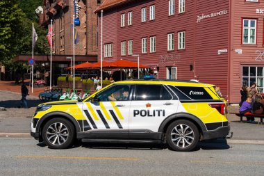 Bergen, Norveç - 9 Temmuz 2024: Politik araç tarihi Bryggen binalarını ve yaz günü şehir merkezinde kalabalık otobüs duraklarını geçiyor