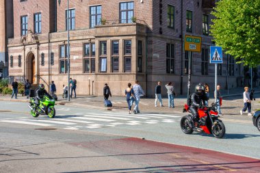 Bergen, Norveç - 9 Temmuz 2024: Yeşil spor bisiklet Kawasaki ve tarihi tuğla bina yakınlarındaki yaya geçidinde üstü açık siyah bisiklet. Güneşli bir günde şehir merkezinde, sokak manzarasında yürüyen yayalar..