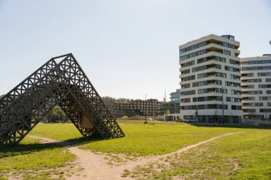 Prag, Çek Cumhuriyeti - 21 Eylül 2024: Mimari ahşap kurulum ile yeni inşa edilen ve ön planda yeşil alan bulunan Diamanty Karlin apartmanları arasındaki şehir kontrastı.