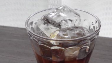 Pencerenin yanındaki masada buzlu kahve resmi.