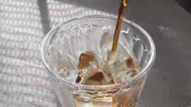 Pencerenin yanındaki masada buzlu kahve resmi.