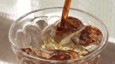 Pencerenin yanındaki masada buzlu kahve resmi.