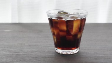 Pencerenin yanındaki masada buzlu kahve resmi.