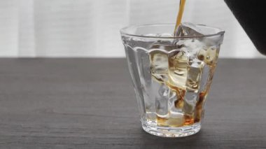 Pencerenin yanındaki masada buzlu kahve resmi.