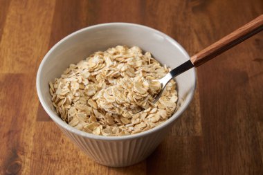 Tahta arka planda ahşap bir kasede yulaf ezmesi, kahvaltı.