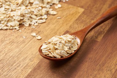 Tahta kaşıkta çiğ yulaf gevreği ve kaşık. Sağlıklı gıda konsepti. Kapat - Seçici odak.