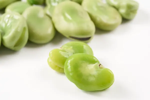 Beyaz arka planda kalp şeklinde yeşil fasulyeler.