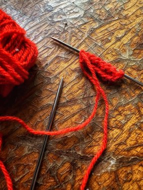 Örgü iğnesinde kırmızı ipliklerle örme işlemi