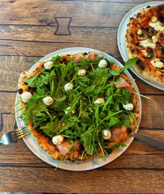 Peynirli, mantarlı, domatesli, mozarella, roka ve fesleğenli pizza.